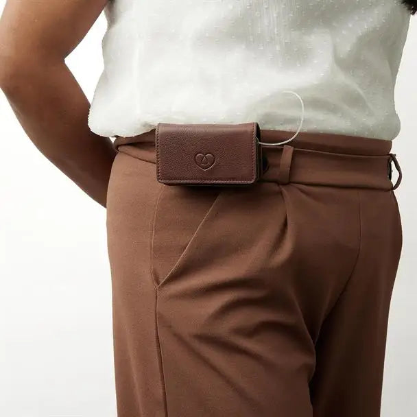 Leather insulin pump bag secured on waistband, featuring lockable flap and magnetic button for easy access.